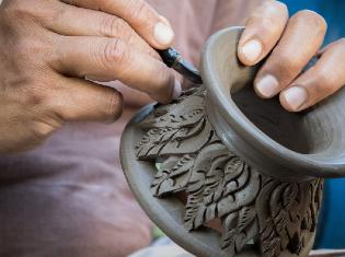 A person crafting a vase out of ceramics.